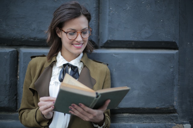 happy-adult-woman-reading-book-with-interest-on-street-3772711 (1)